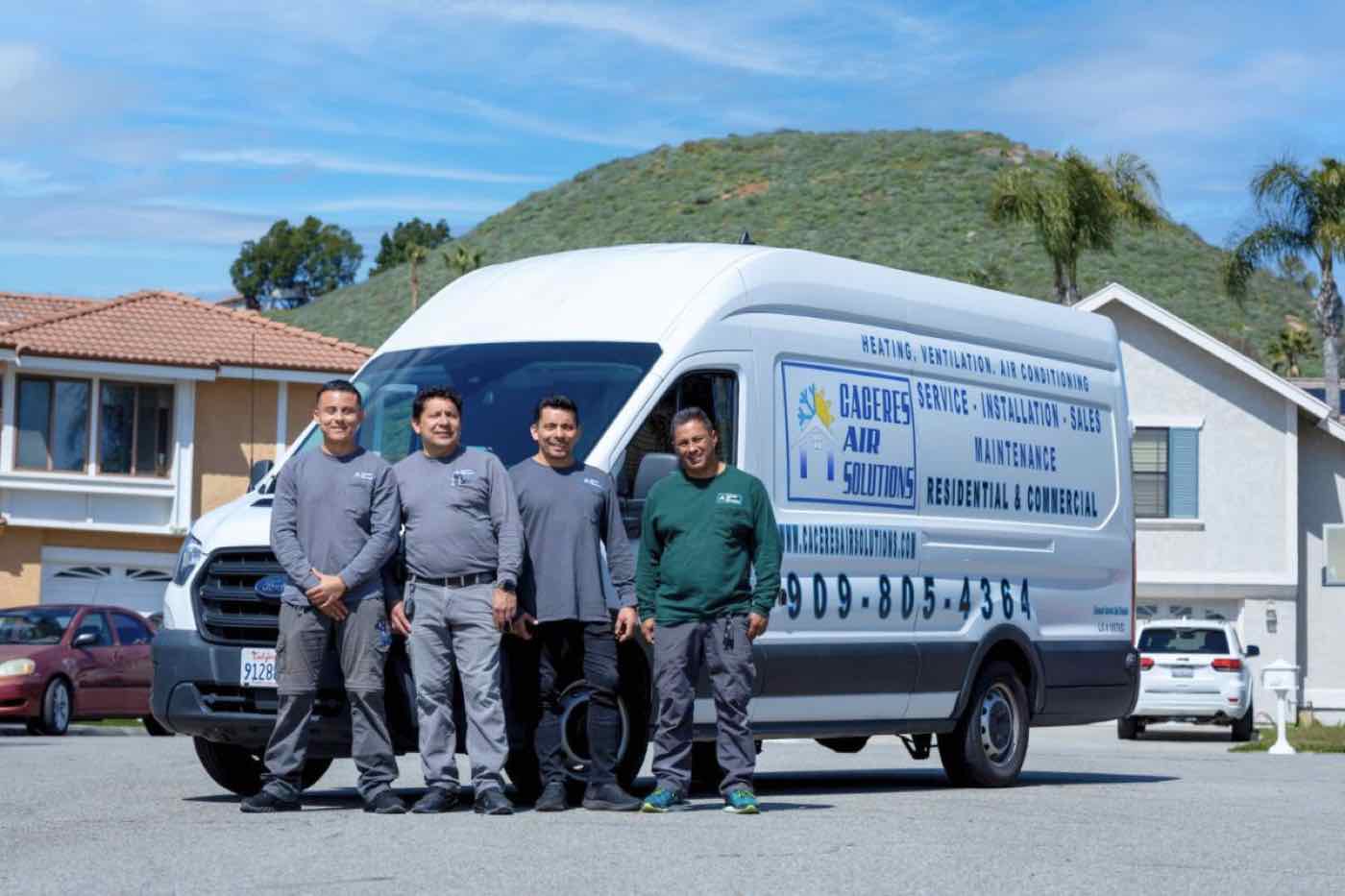 The Caceres Air Solutions crew beside their work van.
