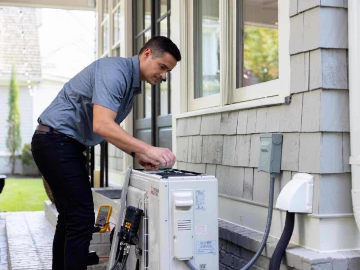 A technician installing an outdoor heat pump unit.
