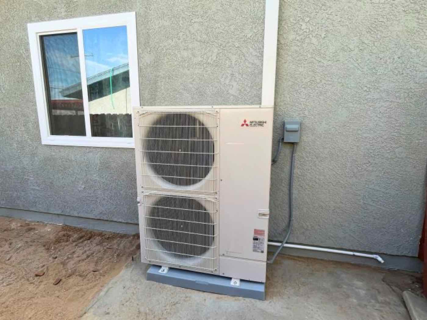 A new outdoor heat pump unit beside a house.