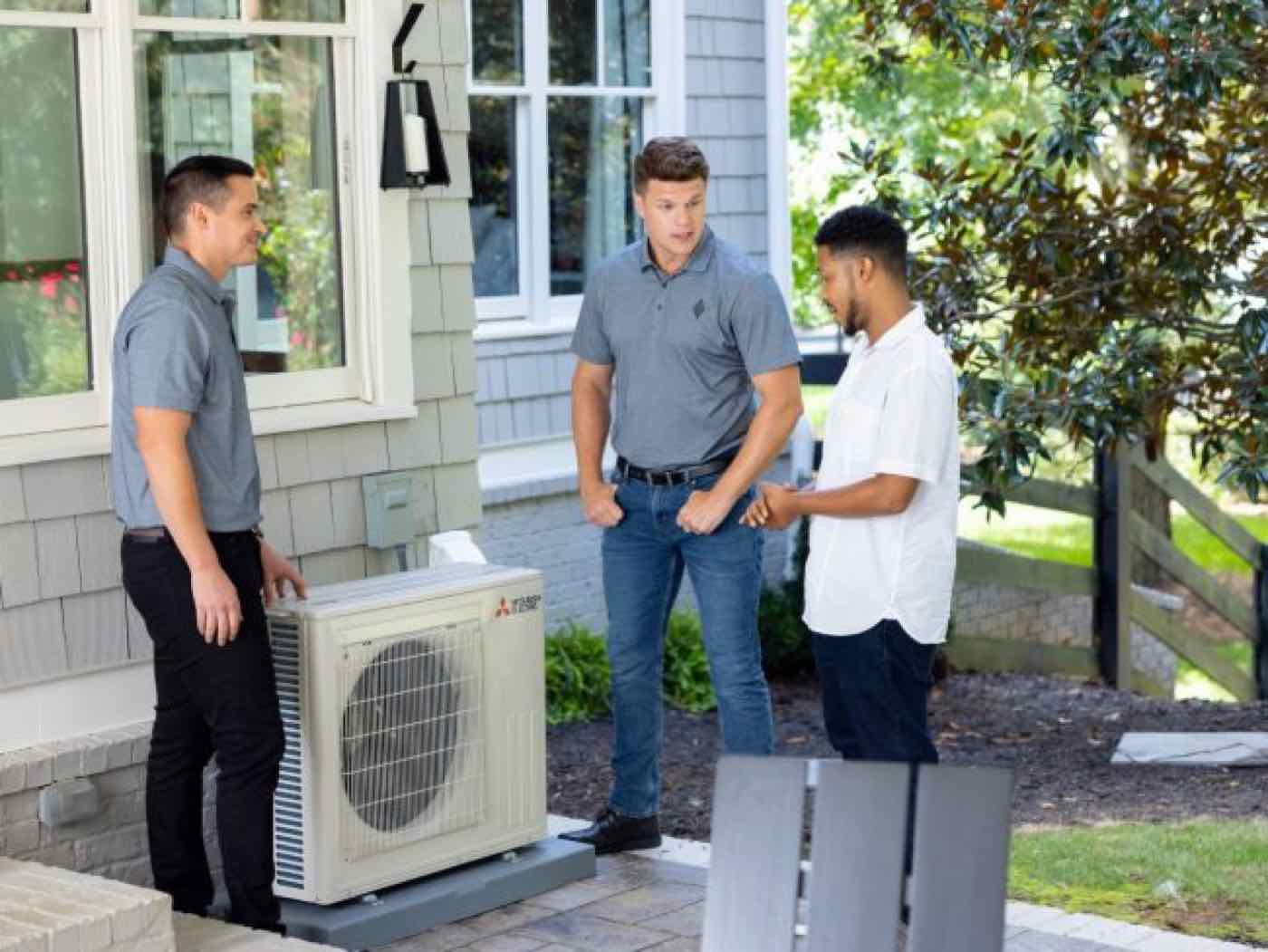 Technicians doing AC maintenance with a homeowner.